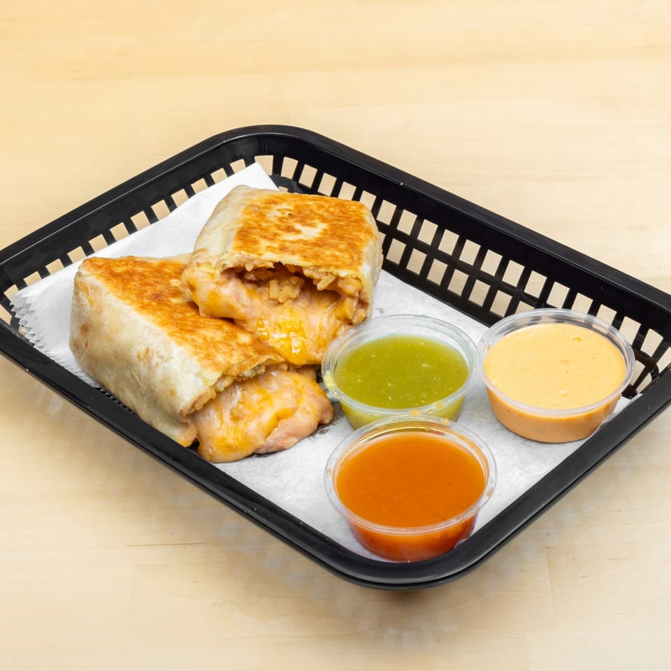 Two golden-brown burritos, one cut open to reveal melted cheese and rice, served with three dipping sauces.